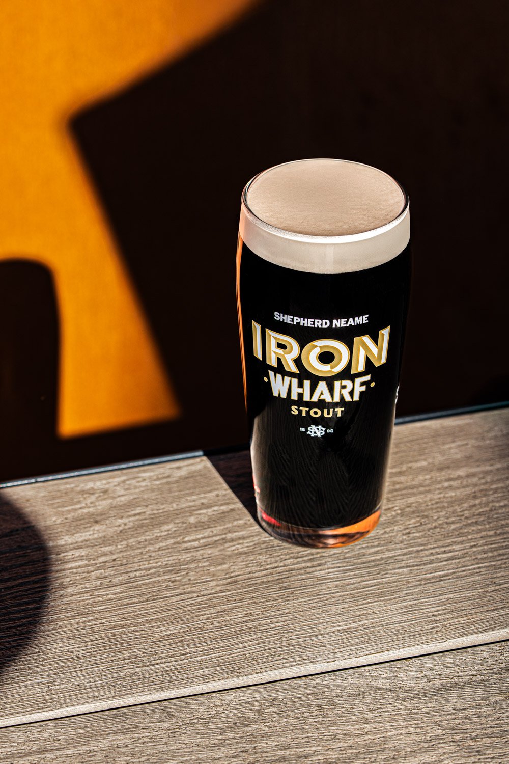 Close-up of a Shepherd Neame Iron Wharf Stout bottle in dramatic low light