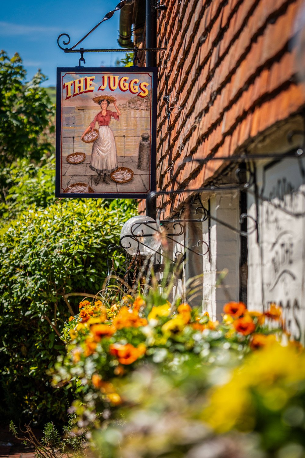 Pub garden with hanging sign and greenery at a Shepherd Neame pub