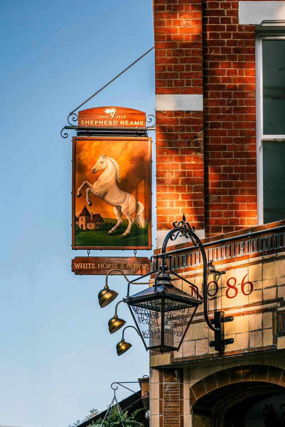 The historic White Horse & Bower, a Shepherd Neame pub in central London. White Horse & Bower Shepherd Neame pub sign in London, featuring a rearing white horse painting on a traditional brick building.