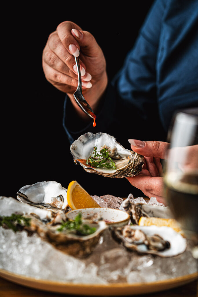 Fresh oysters served on ice with lemon and herbs, finished with sauce in a seafood restaurant