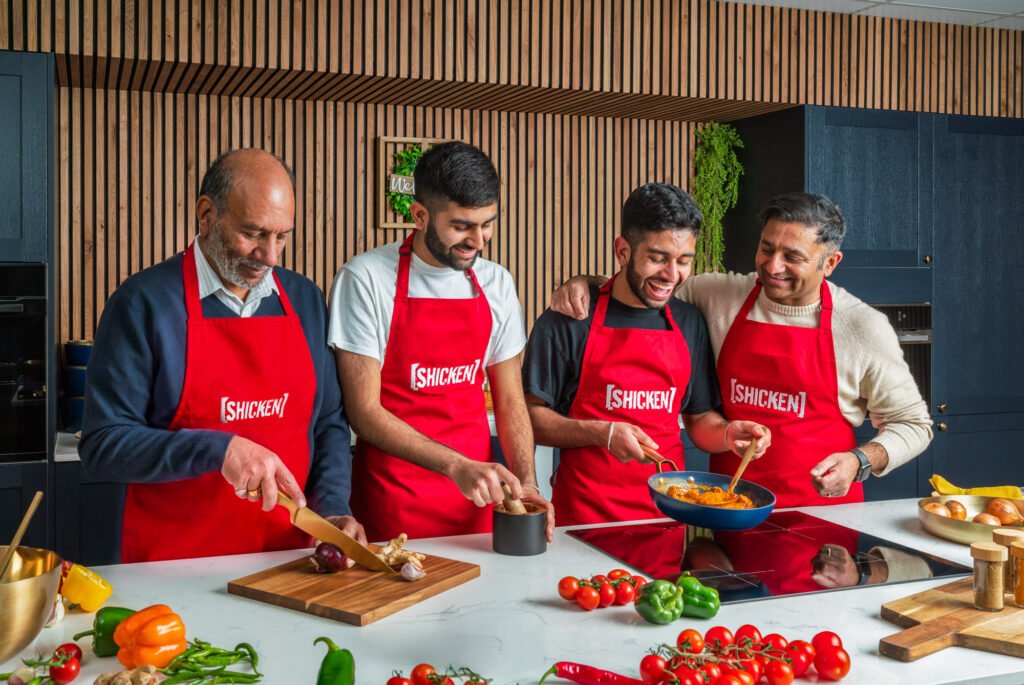 Chefs in red Singha aprons cooking and laughing together at a brand event