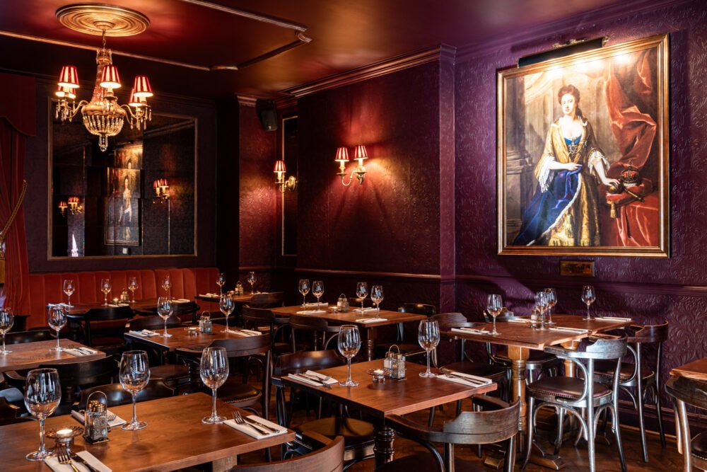 Elegant restaurant interior with deep red walls, chandeliers and classic portrait paintings