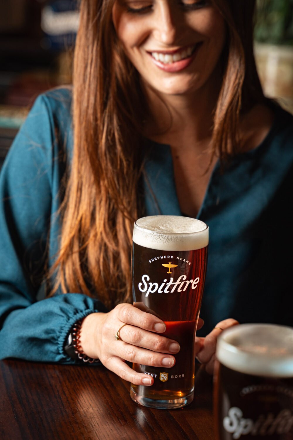 Close-up of a woman holding a pint of Shepherd Neame Spitfire amber ale
