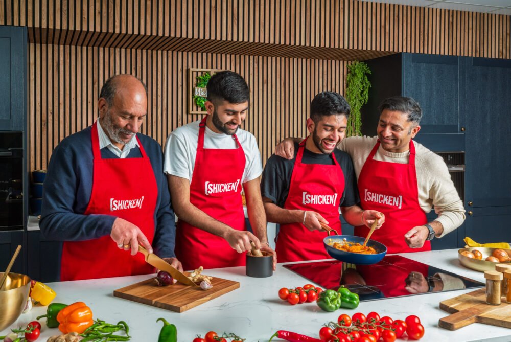 Chefs in red Singha aprons cooking and laughing together at a brand event